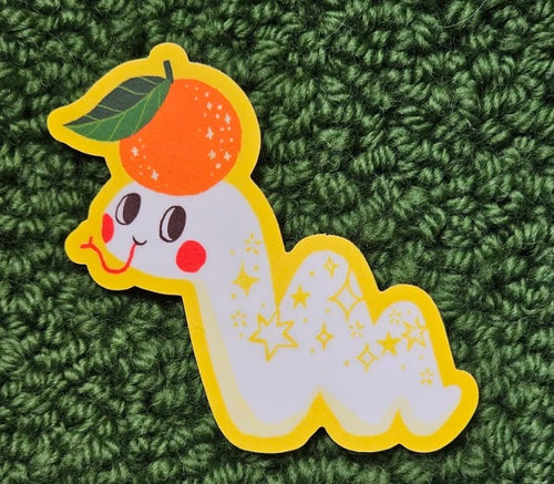 The Lucky Snake Vinyl Single Sticker by Blue Dog Posters features a cartoon worm with red cheeks and a leaf-topped orange hat, its starry yellow-outlined body standing out on green—perfect for adding cute charm anywhere.