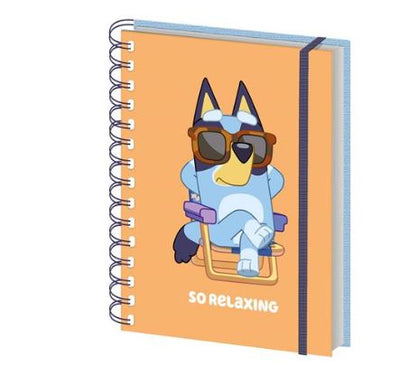 The Bluey So Relaxing Wiro Notebook by Blue Dog Posters is an officially licensed A5 spiral notebook with an orange cover showing a cartoon blue dog in sunglasses, sitting cross-legged in a chair, and "SO RELAXING" at the bottom.