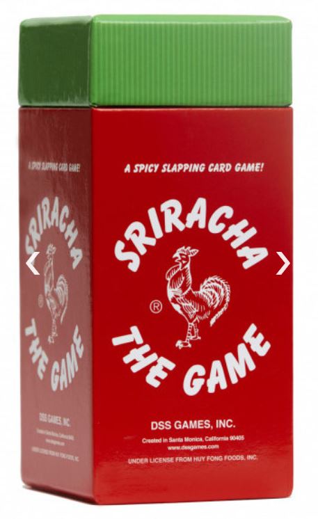 A red and green rectangular box of "Sriracha the Game" with a rooster logo in the center. The text "A spicy slapping card game!" is above the logo and "Sriracha the Game" below. This fast-paced card game from Blue Dog Posters also displays the manufacturer's information and licensing details at the bottom.