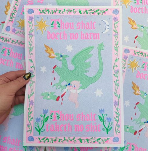 A hand holds the Taketh No Shit A4 Risograph by Amy Hastings from Blue Dog Posters, printed on recycled paper. It features a green dragon, a sword-wielding cat, bold medieval quotes, and pink floral borders. Printed in the UK.