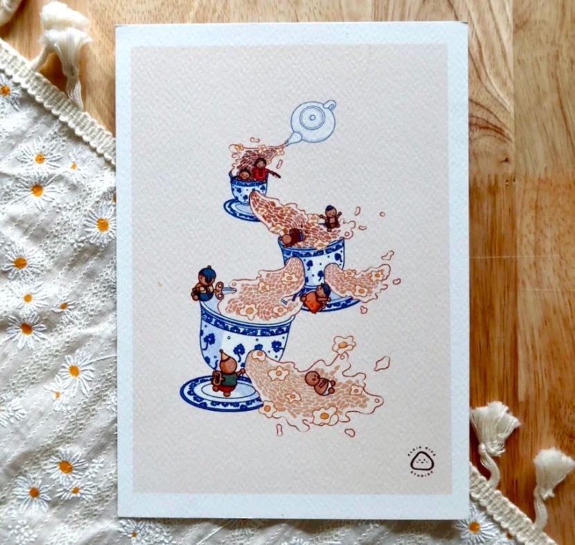 Teacups by Plain Rice Studios from Blue Dog Posters features watercolour art of small animals playing around three stacked teacups with tea, floating leaves, and a teapot above, set on wood beside a floral embroidered cloth.