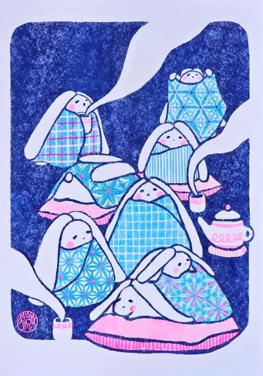Seven adorable white bunnies wrapped in blue blankets share tea, steam wafting from cups and a teapot against a dark blue background in the cozy Tea Time Riso Print by Misu Juju, available from Blue Dog Posters.