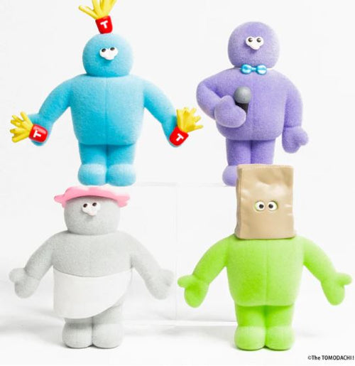 Four vibrant plush toys from the Tomodachi Figure Vol 3 Blind Box by Blue Dog Posters are shown: a blue one with red "T" gloves, a purple with bow tie and mic, a gray in pink hat and skirt, and a green with paper bag over its head.