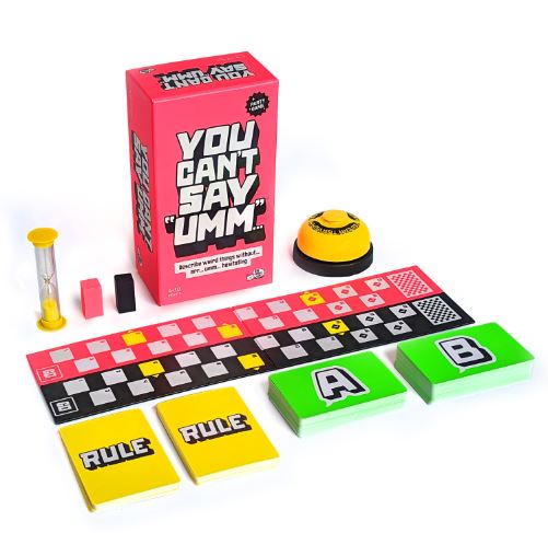 The image shows "You Can't Say Umm" by Blue Dog Posters, featuring a pink box, yellow bell, sand timer, game board, black and pink pieces, yellow Rule cards, and green A & B cards all arranged neatly.