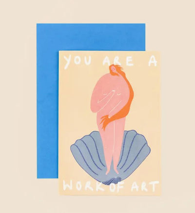 The Work of Art Greeting Card from Blue Dog Posters features a drawing of a nude figure standing on a blue shell with long, flowing orange hair wrapping around them. The light yellow background showcases the text "YOU ARE A WORK OF ART." A blue envelope is behind the card.