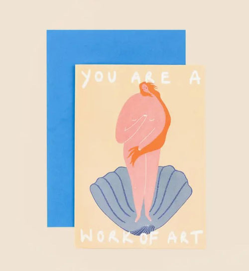 The Work of Art Greeting Card from Blue Dog Posters features a drawing of a nude figure standing on a blue shell with long, flowing orange hair wrapping around them. The light yellow background showcases the text "YOU ARE A WORK OF ART." A blue envelope is behind the card.