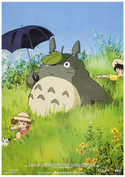 A large creature with grey fur, pointy ears, and a green leaf hat sits in tall grass holding an umbrella. Nearby, a child wearing a hat and red outfit lies on their stomach with a small white creature, while another child peeks from behind the grass. This scene is beautifully captured in our Ghibli - Totoro in the Grass by Y on 250gsm Satin Paper.