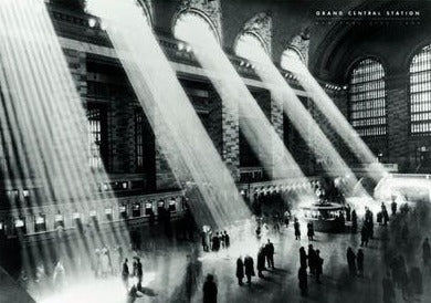 Black and white photo of Grand Central Station's main concourse, showing rays of sunlight streaming through large arched windows. People move across the polished floor, creating a bustling yet ethereal atmosphere in the iconic New York City landmark, perfect for a scenic collection or cityscape poster. **NAT 044 - Grand Central Station**.
