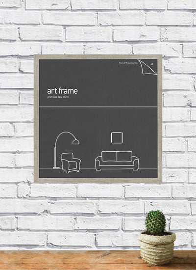 A Classic Frame 60x60cm Ash by Blue Dog Posters, featuring a minimalist line drawing of a living room setup with a floor lamp, armchair, couch, and picture, is mounted on a white brick wall. Part of our Large Frames Collection for 60cm x 60cm posters. Below the frame sits a small cactus in a pot on a wooden surface.