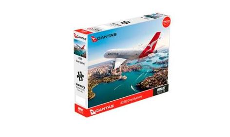 A photograph of a Qantas A380 Over Sydney 1000pc Puzzle box. The officially licensed box features an image of a Qantas aircraft flying over Sydney Harbour with the Sydney Opera House and Harbour Bridge in the background. Labeled "Qantas A380 Over Sydney 1000pc Puzzle" with Blue Dog Posters branding, it makes a perfect addition to any giftware collection.