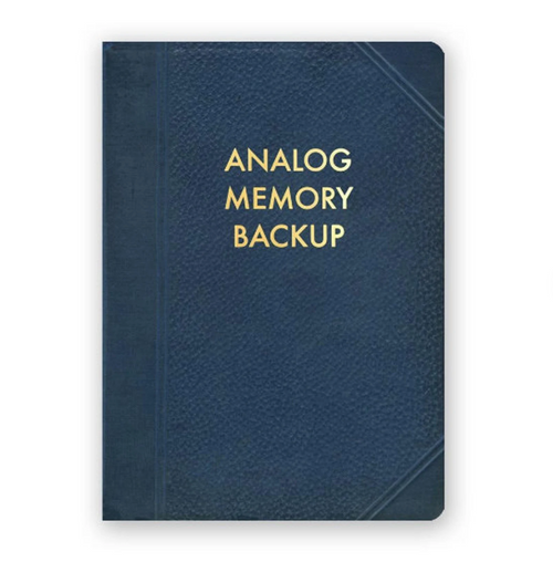 The Blue Dog Posters' Analog Memory Backup Journal is a dark blue, hardcover journal with "ANALOG MEMORY BACKUP" printed in bold yellow uppercase letters on the front cover. The textured design of the cover features intricate geometric patterns near the edges.
