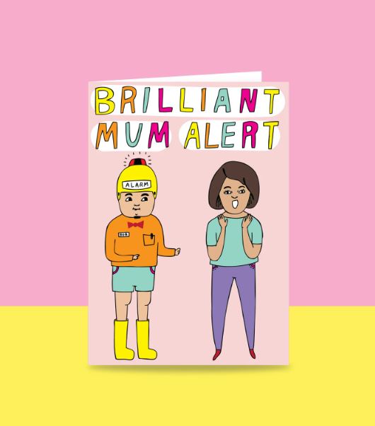 This Mother's Day, give a Blue Dog Posters' "Brilliant Mum Alert Greeting Card." The card boasts a colorful split pink and yellow background design with the text "BRILLIANT MUM ALERT" prominently displayed. It features two whimsical cartoon characters: one wearing a helmet labeled "ALARM," dressed in shorts, boots, and a bow tie, and the other standing thoughtfully. This unique piece is part of our exclusive giftware collection.