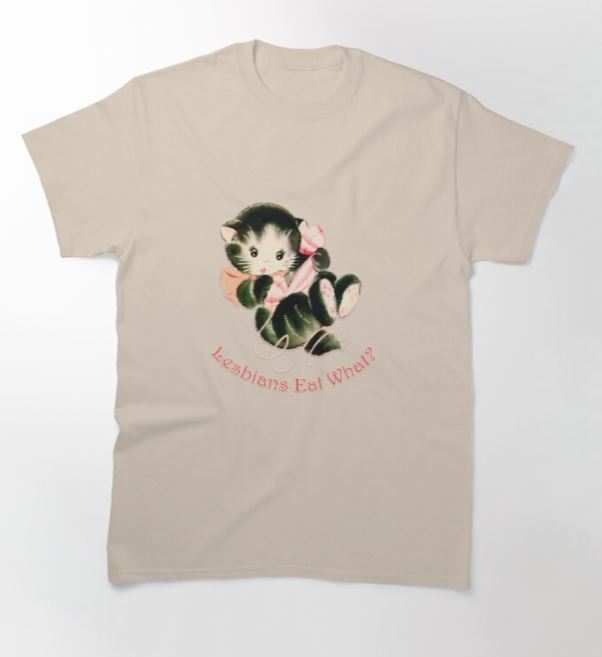 The Lesbians Eat What T-Shirt NAT MED from Blue Dog Posters is a super cool beige t-shirt featuring a design of a cute kitten holding a candy cane. Below the kitten, the text "Lesbians Eat What?" is written in a whimsical pink font and is available in sizes S, M, and L from Hustle and Co.