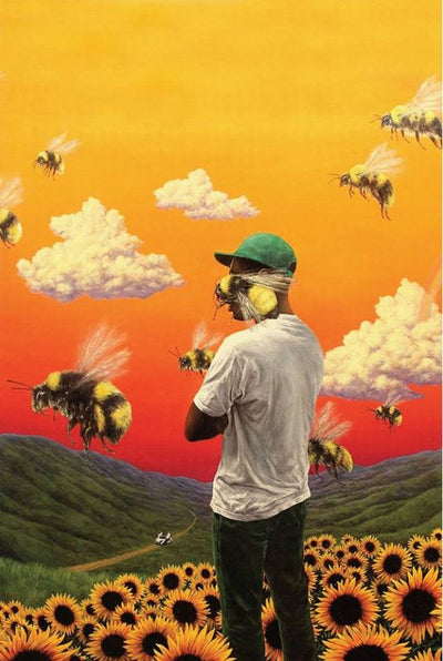 A person in a green cap and white shirt stands in a sunflower field with green hills in the background. Giant bees and fluffy clouds, under an orange-yellow sky, surround them, creating a surreal element. Resembling the vibrant and unreal style of the Tyler The Creator Poster Flowerboy by MUS 046, this scene feels like something out of an avant-garde Hip Hop poster.